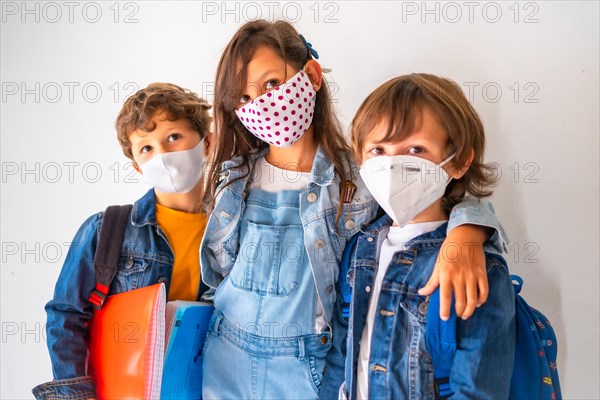 Three children with face masks ready to go back to school. New normality