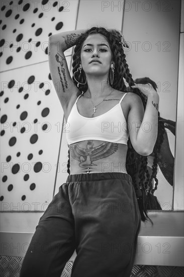 Young woman of black ethnicity with long braids and with tattoos