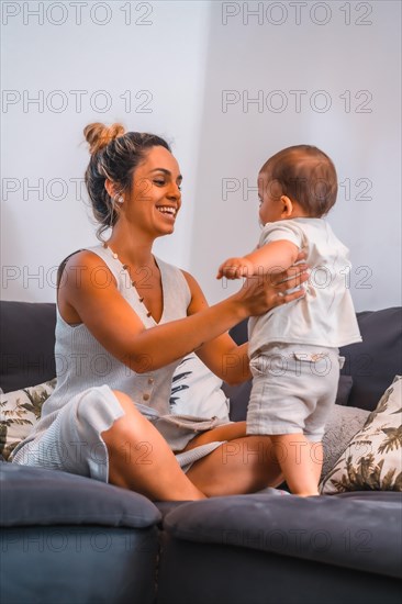 Young Caucasian mother with her son sitting on the black sofa in their home. Teleworking and caring for your child