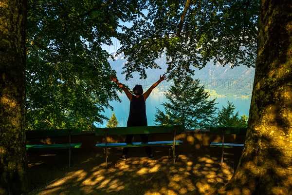 Woman with Arms Outstretched in Front of Lake Brienz with Mountain in Giessbach