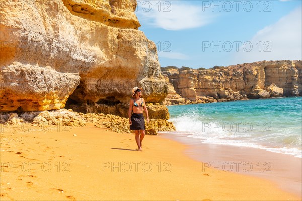 A woman with a hat in the Algarve on the beach at Praia da Coelha