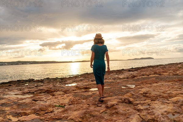 A young woman with a hat at sunset on the Paseo de Poniente in San Antonio Abad