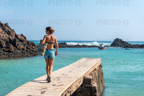 A young woman walking along the wooden walkway on the Isla de Lobos