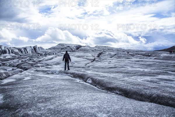 A young man on her back with booties and hammer on the trekking of the Svinafellsjokull glacier. Iceland