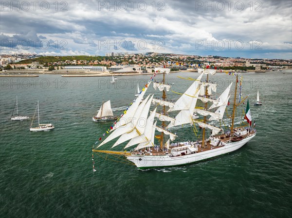 Aerial drone view of tall ships with sails sailing in Tagus river towards the Atlantic ocean in Lisbon