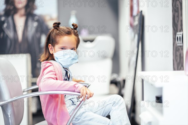 Girl sitting on the chair with pigtails finished. Reopening with security measures for hairdressers in the Covid-19 pandemic