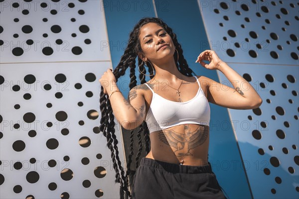 Young woman of black ethnicity with long braids and tattoos