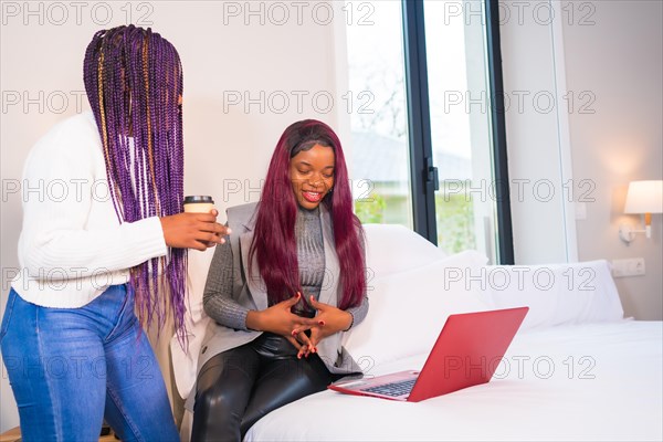 Young businesswomen of black ethnicity. Telecommuting and having fun with a laptop from a hotel room