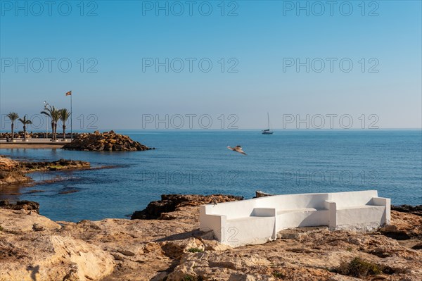 A white seat by the sea in the coastal town of Torrevieja next to Playa del Cura