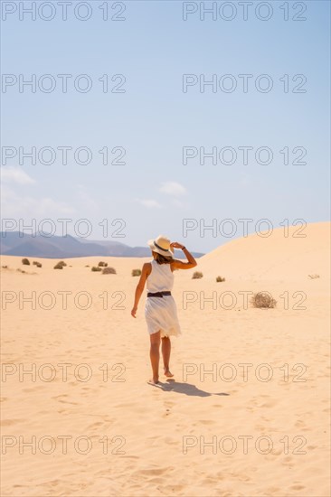A young tourist wearing a hat walking along the sand on the beaches of the Corralejo Natural Park