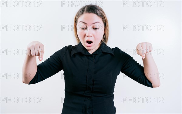 Surprised young woman pointing at advertising down isolated. Shocked latin girl pointing down a promotion