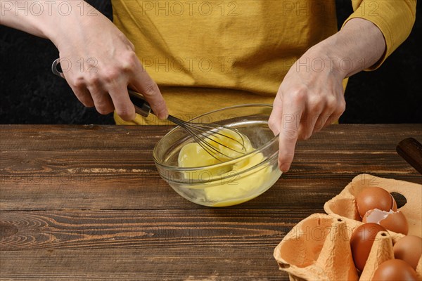 Unrecognizable man whisking eggs in a glass bowl while making an omelet