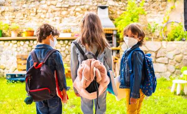 Three brother children with face masks ready for going back to school. New normality