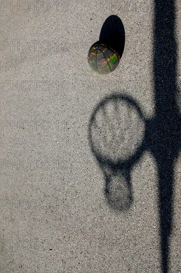 Shadow of a Basketball Hoop and a Real Basket Ball Against the Ground with Sunlight in Switzerland