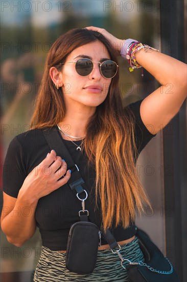 Beautiful young brunette caucasian businesswoman outside the office building walking. With green skirt and sunglasses looking for the sides