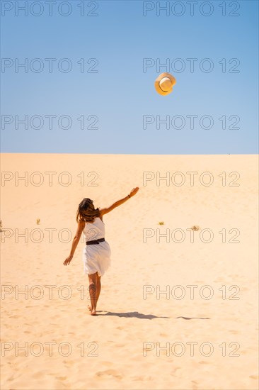 Tourist throwing his hats up very happy in the dunes of the Corralejo Natural Park