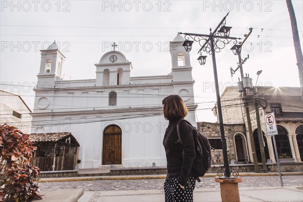 A young woman looking at the white church of Copan Ruinas. Honduras