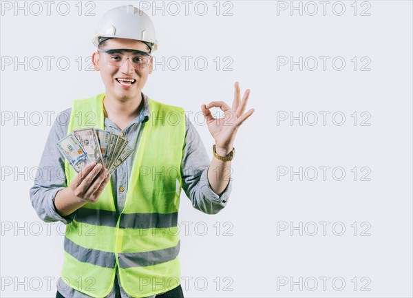 Smiling engineer constructor holding money gesturing ok isolated. Latin engineer showing money making gesture ok isolated
