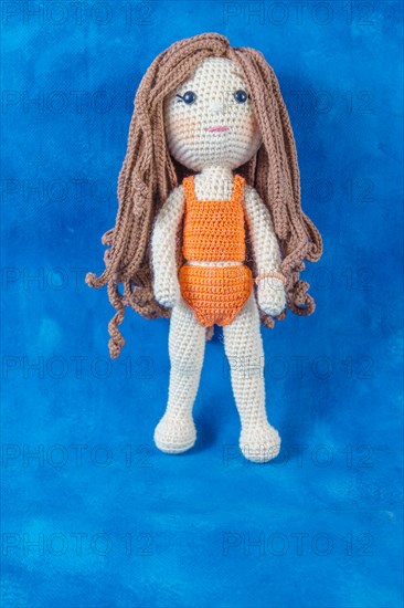 Close-up of a handmade amigurumi doll on a blue background