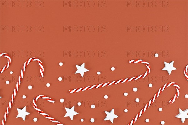 Christmas flat lay with candy canes and star and snow ornaments on brown background with empty copy space