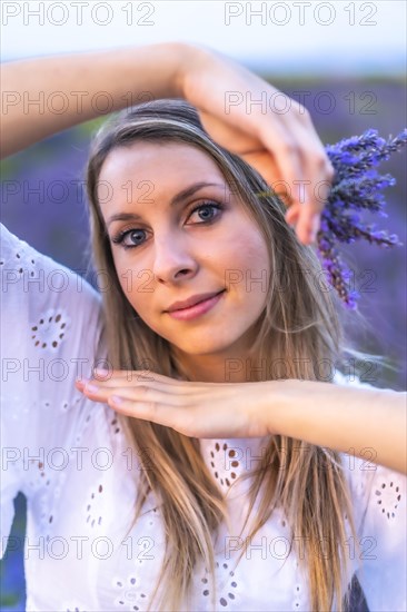 A young blonde Caucasian woman in a white dress in a cultivated lavender field in Navarra