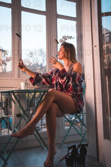 Lifestyle of a young blonde woman having breakfast next to the sale of her house. Dressed in underwear and pajamas