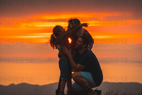 A family hugging and having fun on the top of a mountain at sunset. Adventure lifestyle A summer afternoon in the mountains of the Basque country