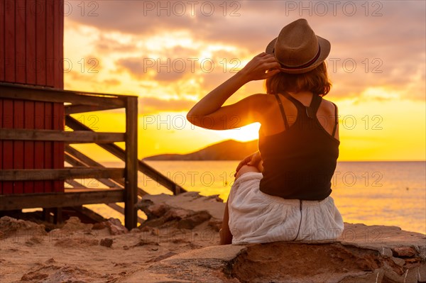 Young woman with hat at sunset in Cala Comte beach on the island of Ibiza. Balearic