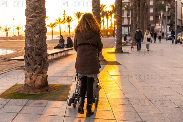 Mother strolling at sunset on Playa del Cura in the coastal town of Torrevieja