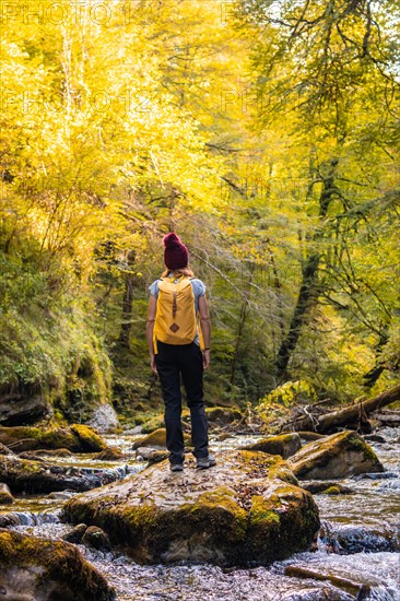 A young woman at sunset on the river on the path to the Holtzarte suspension bridge