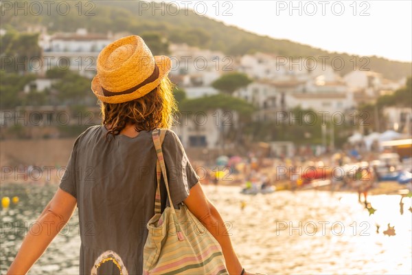 A young tourist with a hat at sunset on the coast of Tamariu in the town of Palafrugell. Girona