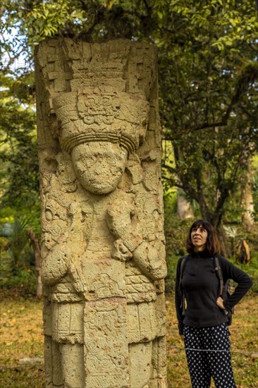 A woman in to detail of a figure in The temples of Copan Ruinas. Honduras