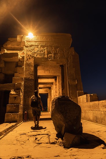 A young man visiting the illuminated Kom Ombo Temple at night