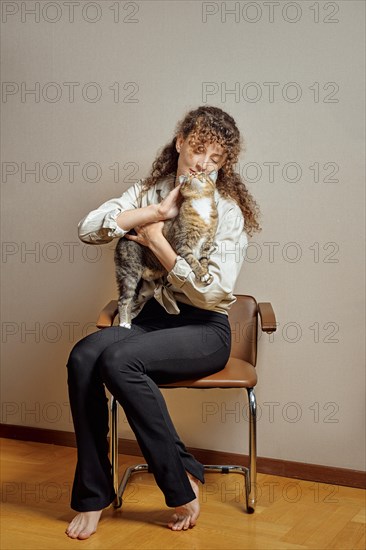 Barefoot young woman playing with cat