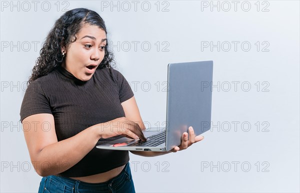 Amazed latin woman using laptop isolated. Surprised girl looking at an promotion on laptop screen