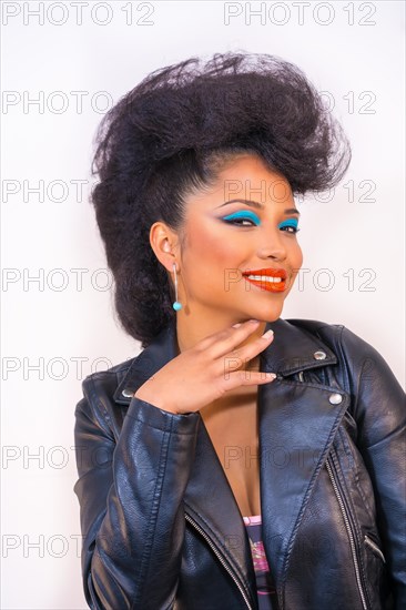 A vertical shot of a young Latin woman in retro disco look with a leather jacket and brmakeup