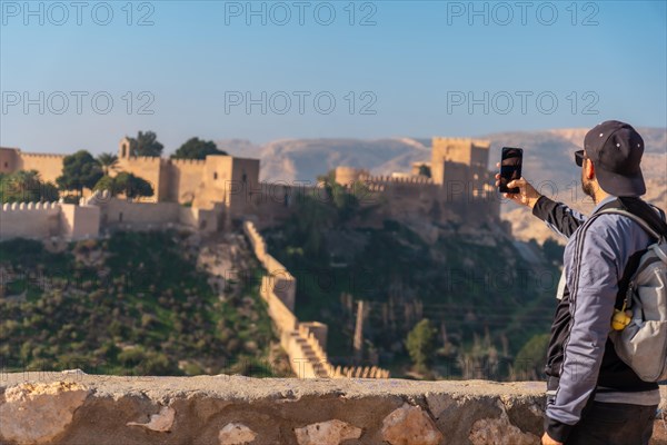 A young tourist taking a photo at the viewpoint of Cerro San Cristobal de la Muralla de Jairan and the Alcazaba in the town of Almeria