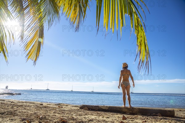 A young girl on top of a log on West End beach on Roatan Island. Honduras