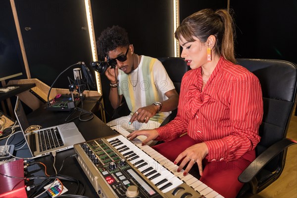 Pianist recording a new song in a studio with the help of a technician