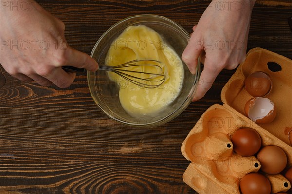 Unrecognizable man whisking eggs in a glass bowl