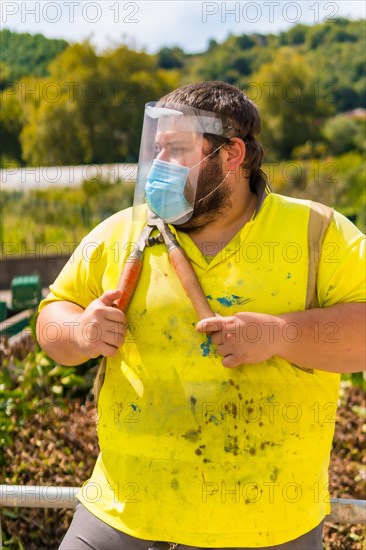 Worker in a recycling factory or clean point and garbage with a face mask and plastic protective screen