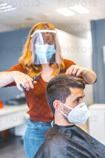 Hairdressers after the Coronavirus pandemic. Caucasian hairdresser with face mask and protective screen