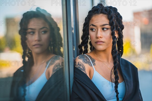 Urban session. Young woman of black ethnicity with long braids and with tattoos