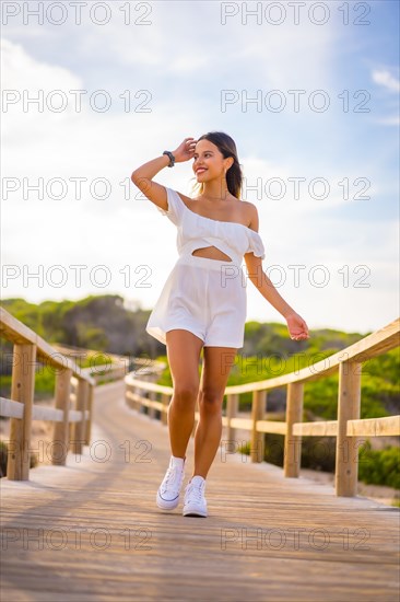 Lifestyle of a young brunette Caucasian enjoying the beach vacation in a white dress in summer