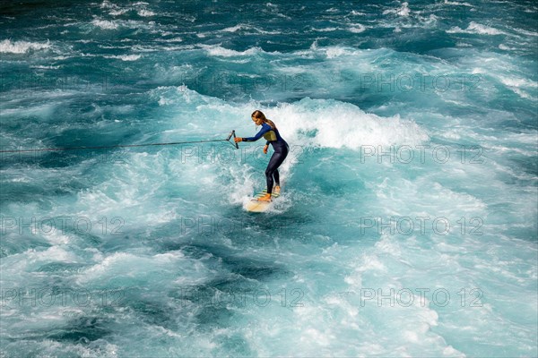 Surfer Surfing the Wave on River Aare in City of Thun in a Sunny Summer Day in Thun