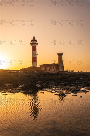 Sunset at the Toston Lighthouse near the sea with the reflected lighthouse