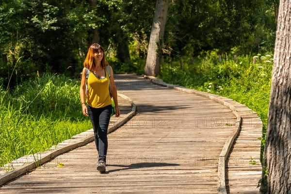 A young woman trekking on the footpath along a footbridge between La Garette and Coulon