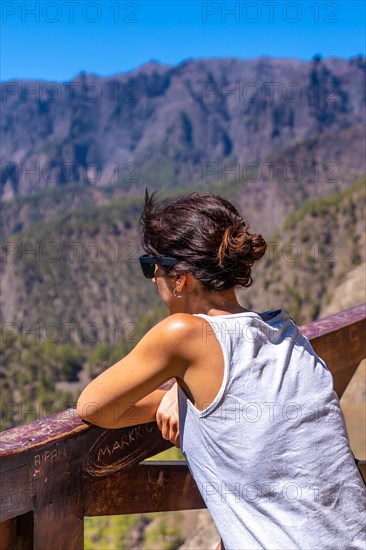 A young tourist looking at the landscape at the Mirador de los Roques on the La Cumbrecita mountain on the island of La Palma next to the Caldera de Taburiente