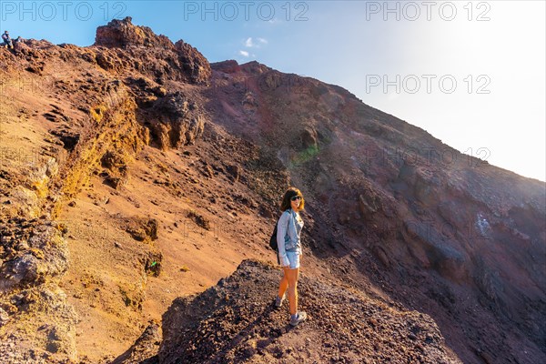 A young woman looking at the crater of the Teneguia volcano on the route of the volcanoes