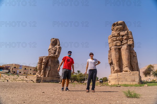 A couple visiting two Egyptian sculptures in the city of Luxor along the Nile. Egypt